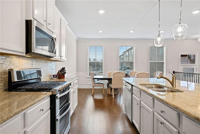 kitchen with a sink, appliances with stainless steel finishes, decorative backsplash, dark wood-style floors, and crown molding