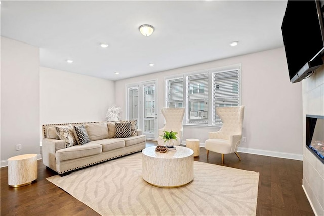 living area featuring dark wood-style floors, recessed lighting, a glass covered fireplace, and baseboards