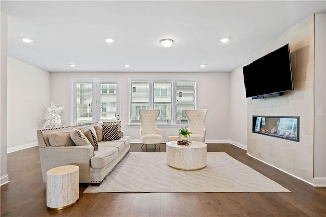 living room with dark wood-type flooring, recessed lighting, a tile fireplace, and baseboards