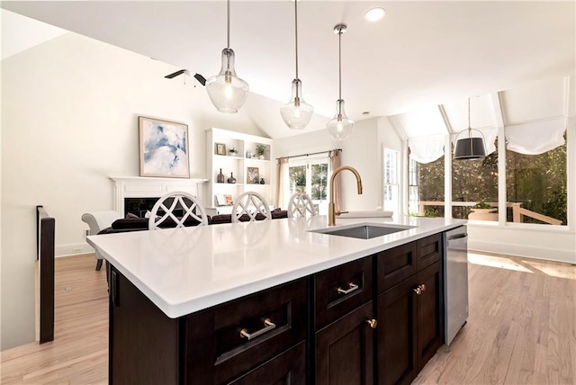 kitchen with lofted ceiling, a sink, light countertops, light wood-style floors, and open floor plan