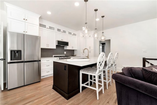 kitchen featuring light wood-style floors, light countertops, a kitchen bar, and stainless steel refrigerator with ice dispenser