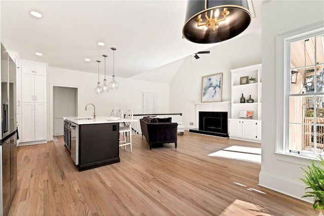 kitchen with a kitchen bar, light countertops, light wood-style flooring, white cabinetry, and a sink