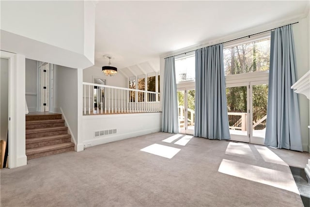 carpeted spare room with visible vents, plenty of natural light, a chandelier, and stairway