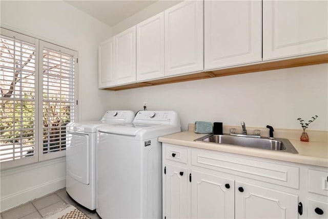 clothes washing area with light tile patterned floors, baseboards, separate washer and dryer, cabinet space, and a sink