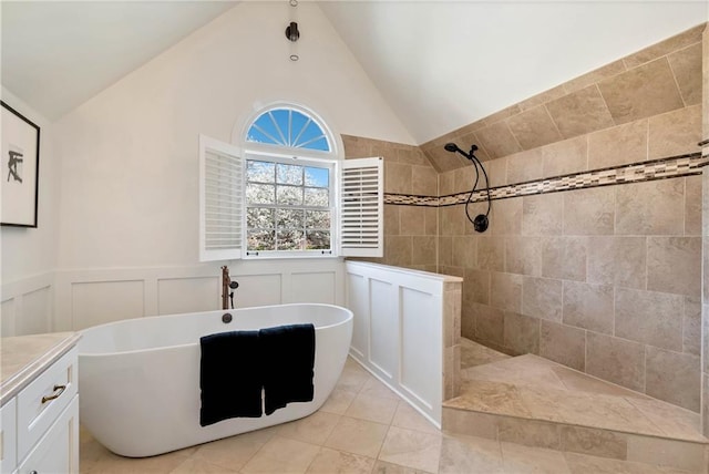 bathroom featuring a wainscoted wall, a freestanding bath, tile patterned flooring, vaulted ceiling, and walk in shower