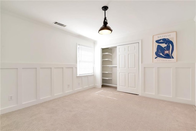 unfurnished bedroom featuring a closet, a decorative wall, visible vents, and carpet