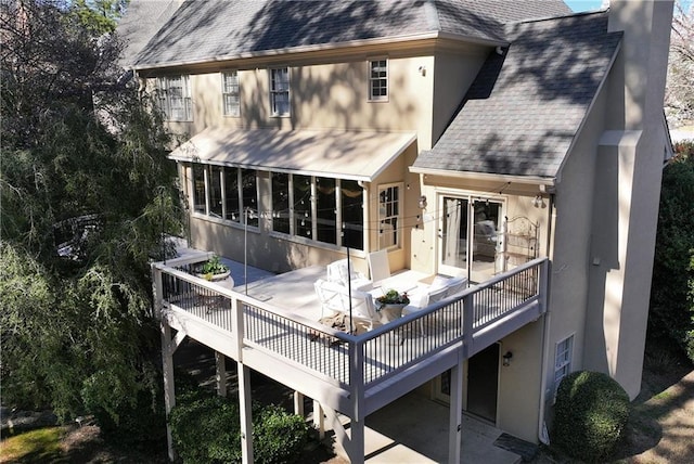 rear view of property featuring stucco siding, a chimney, roof with shingles, and a sunroom