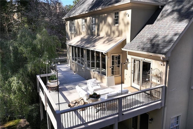 back of house with stucco siding, roof with shingles, and a sunroom