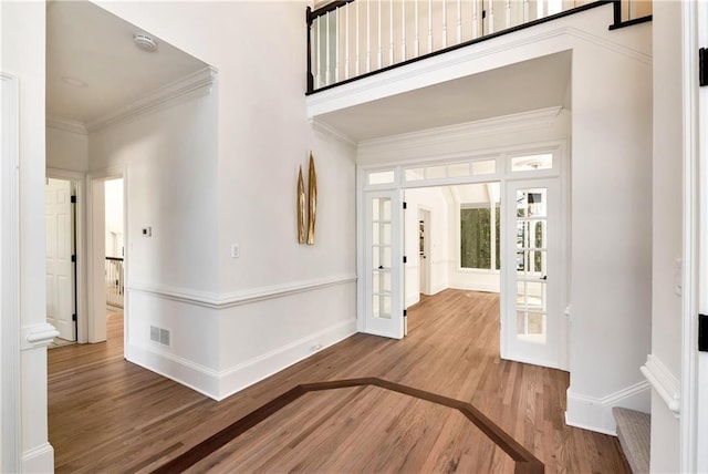 foyer with wood finished floors, visible vents, baseboards, french doors, and crown molding