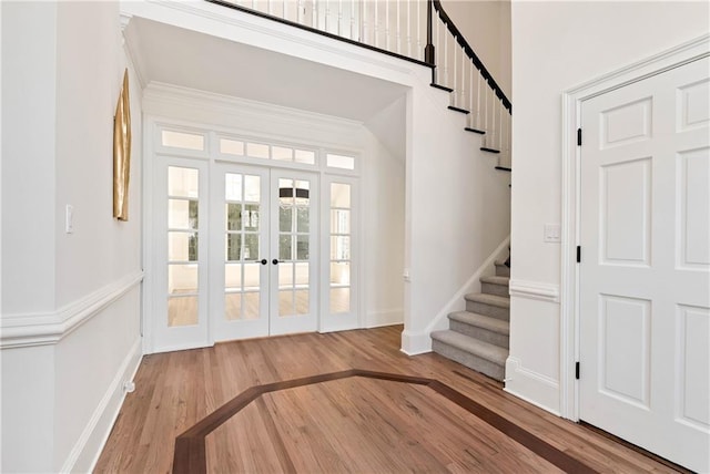 foyer with stairway, wood finished floors, baseboards, and french doors