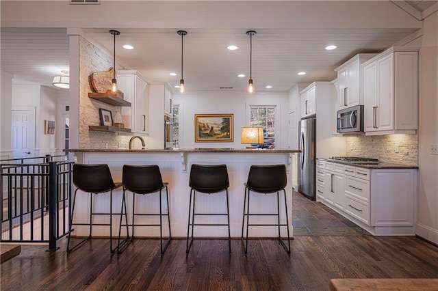 kitchen featuring white cabinets, a breakfast bar, a peninsula, stainless steel appliances, and open shelves