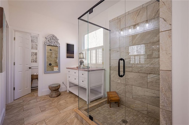 full bathroom with a stall shower, baseboards, and vanity