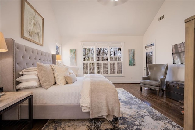 bedroom with high vaulted ceiling, wood finished floors, visible vents, and baseboards