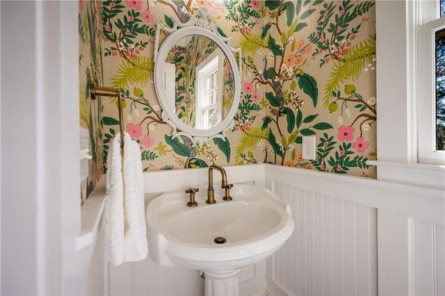 bathroom featuring a sink and wallpapered walls