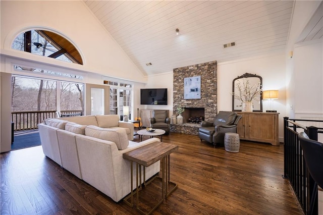 living room with dark wood-style floors, high vaulted ceiling, a stone fireplace, and a wealth of natural light