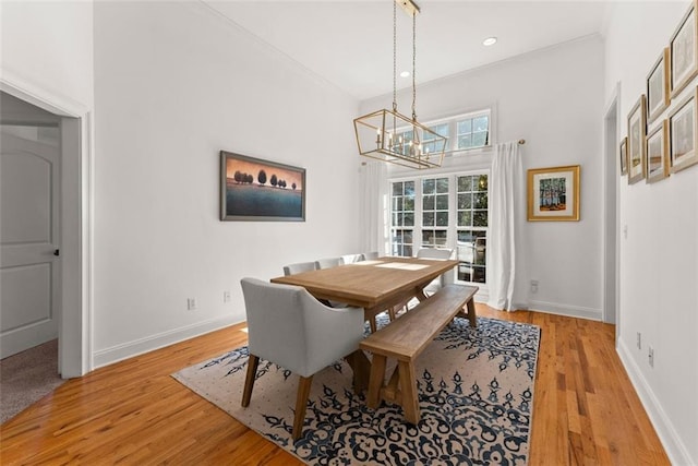 dining space with light wood-type flooring, an inviting chandelier, and ornamental molding