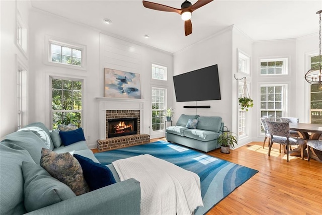 living room with ceiling fan, a fireplace, a towering ceiling, and wood-type flooring