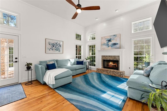 living room with hardwood / wood-style floors, a brick fireplace, plenty of natural light, and ceiling fan