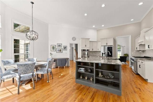 kitchen with white cabinets, tasteful backsplash, stainless steel appliances, and an island with sink