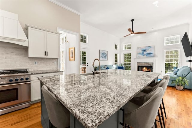 kitchen featuring a breakfast bar, high end stainless steel range oven, ceiling fan, custom range hood, and white cabinetry