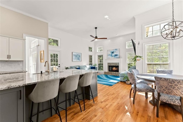 kitchen featuring light stone countertops, a brick fireplace, sink, white cabinets, and hanging light fixtures