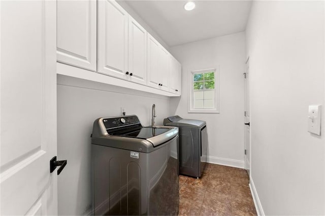 laundry area featuring washing machine and clothes dryer and cabinets