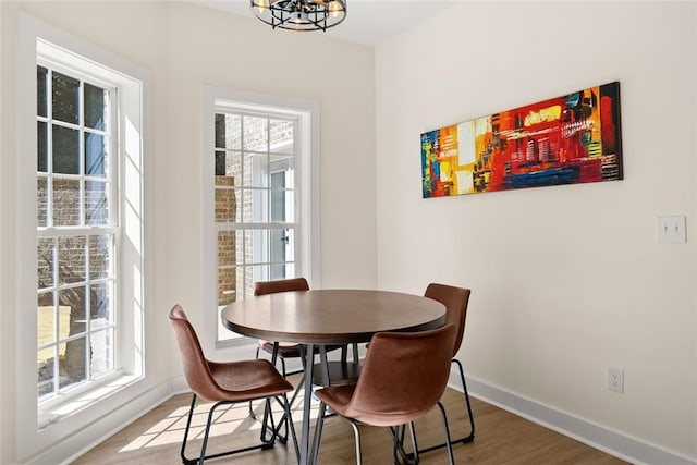 dining room featuring wood-type flooring, plenty of natural light, and a notable chandelier