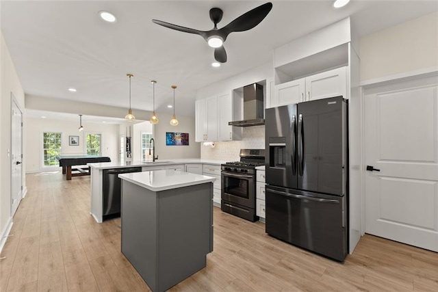 kitchen featuring kitchen peninsula, stainless steel appliances, sink, wall chimney range hood, and white cabinetry