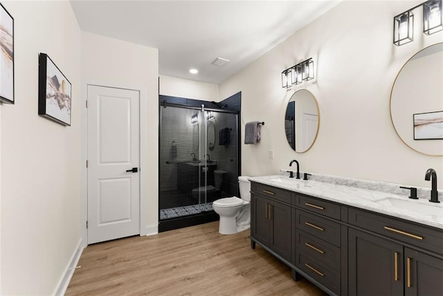 bathroom featuring toilet, vanity, a shower with shower door, and hardwood / wood-style flooring