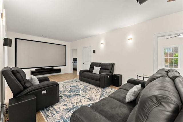 cinema with ceiling fan and light wood-type flooring