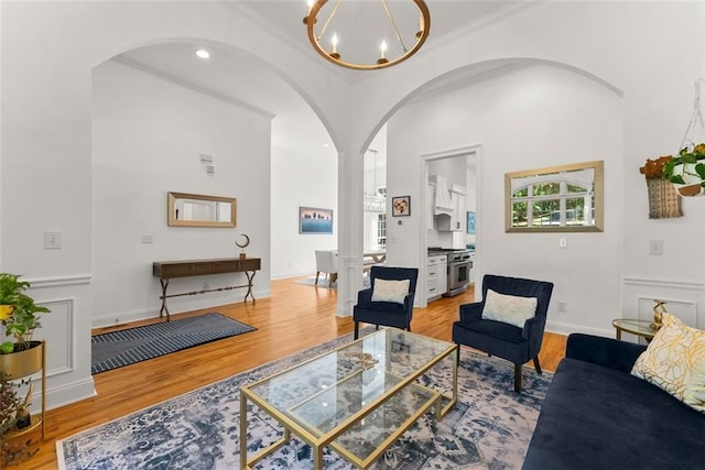 living room with crown molding, a chandelier, and light wood-type flooring