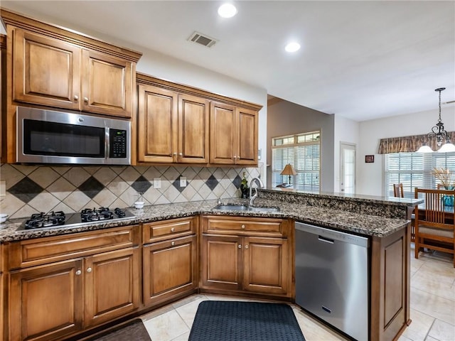 11 Stillwater Way, Hoschton, GA 30548 - kitchen with stainless steel appliances, a peninsula, backsplash, brown cabinetry, and recessed lighting