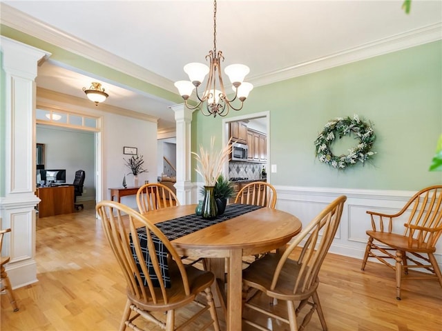 11 Stillwater Way, Hoschton, GA 30548 - dining room featuring ornate columns, light wood-style flooring, crown molding, a wainscoted wall, and a chandelier