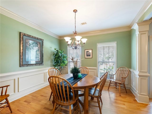 11 Stillwater Way, Hoschton, GA 30548 - dining space with decorative columns, a chandelier, light wood-type flooring, a decorative wall, and crown molding