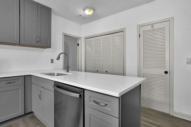 kitchen with stainless steel dishwasher, gray cabinets, kitchen peninsula, and sink