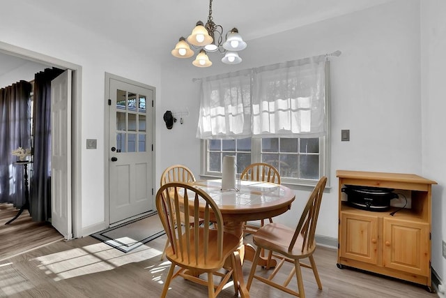 dining space with light hardwood / wood-style flooring and an inviting chandelier