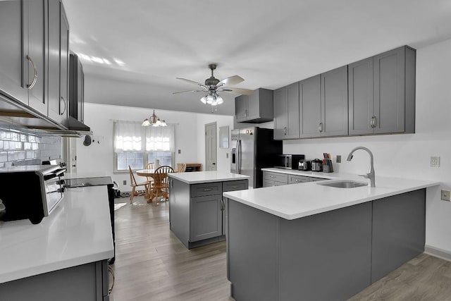 kitchen featuring gray cabinets, kitchen peninsula, sink, and stainless steel refrigerator with ice dispenser