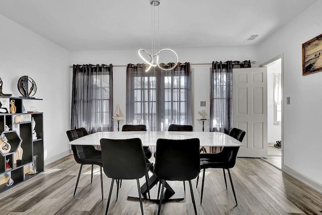 dining room with light hardwood / wood-style floors and a chandelier