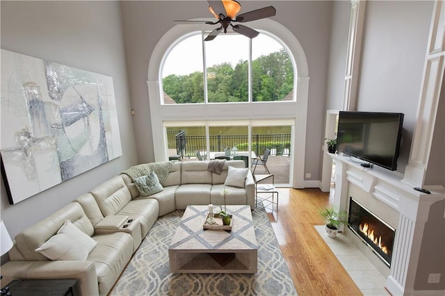 2675 Portabella Ln, Cumming, GA 30041 - living area featuring a ceiling fan, a high ceiling, a tiled fireplace, and light wood finished floors