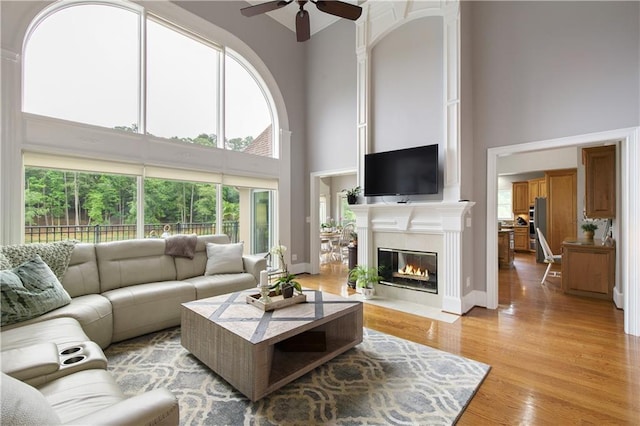 2675 Portabella Ln, Cumming, GA 30041 - living area featuring a high ceiling, ceiling fan, a fireplace with flush hearth, and light wood-style floors