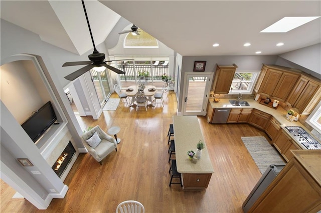 2675 Portabella Ln, Cumming, GA 30041 - living room with ceiling fan, lofted ceiling, light wood-style floors, a warm lit fireplace, and a skylight