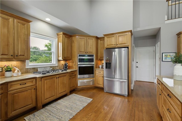 2675 Portabella Ln, Cumming, GA 30041 - kitchen featuring appliances with stainless steel finishes, a towering ceiling, a warming drawer, backsplash, and dark wood-style floors
