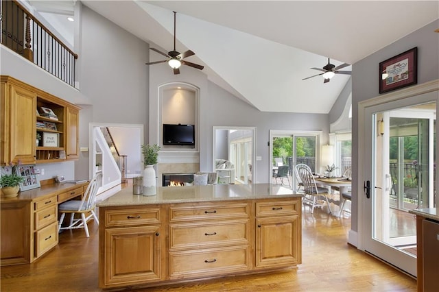 2675 Portabella Ln, Cumming, GA 30041 - kitchen featuring a ceiling fan, light wood-type flooring, a warm lit fireplace, and high vaulted ceiling