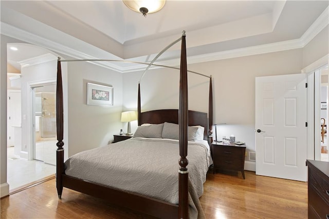 2675 Portabella Ln, Cumming, GA 30041 - bedroom with light wood-type flooring, a tray ceiling, crown molding, connected bathroom, and baseboards