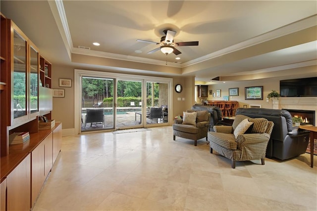 2675 Portabella Ln, Cumming, GA 30041 - living area with a tray ceiling, a ceiling fan, crown molding, a warm lit fireplace, and baseboards
