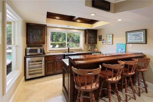 2675 Portabella Ln, Cumming, GA 30041 - indoor bar with wine cooler, ornamental molding, stainless steel microwave, tasteful backsplash, and healthy amount of natural light