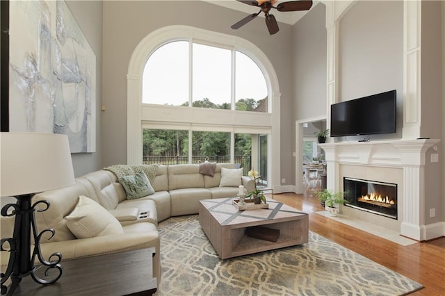 2675 Portabella Ln, Cumming, GA 30041 - living area featuring a ceiling fan, a tile fireplace, light wood-style flooring, a high ceiling, and baseboards