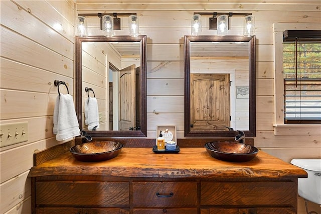 bathroom with wooden walls, vanity, and toilet