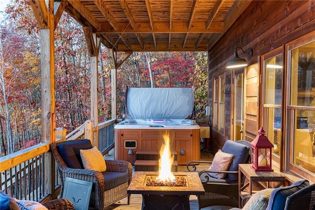 wooden terrace with an outdoor fire pit and a hot tub