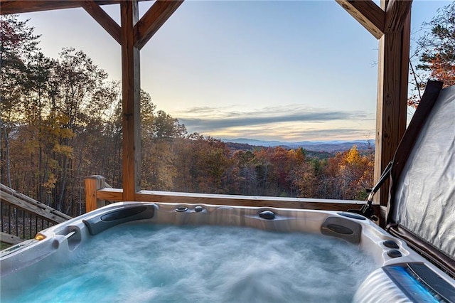 pool at dusk featuring a hot tub